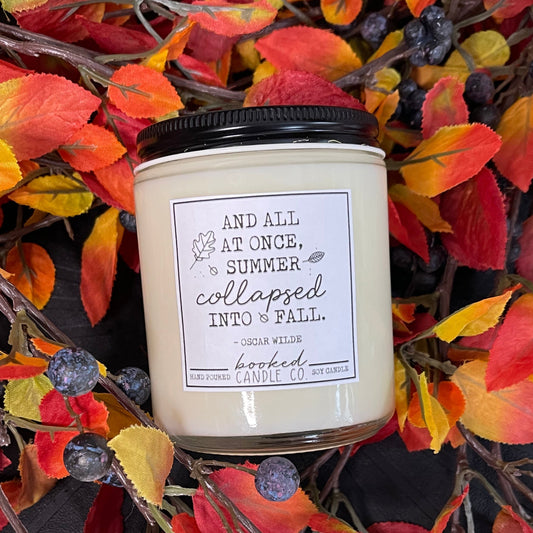 Candle with a label with an Oscar Wilde quote surrounded by autumn leaves and berries