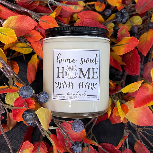 Candle with a 'home sweet home' label surrounded by autumn leaves and berries