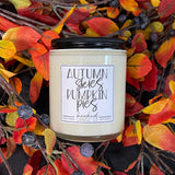 Candle with 'Autumn Skies Pumpkin Pies' label on a decorative wreath with fall leaves and berries