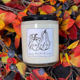 Candle with 'Grateful' label surrounded by autumn leaves and berries