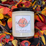 Candle with a 'thankful' label surrounded by autumn leaves and berries