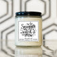 Candle jar with a label reading 'Snuggle and watch it snow' on a reflective surface with a geometric background.