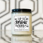 Candle jar with 'Up to Snow Good' label on a reflective surface with geometric background